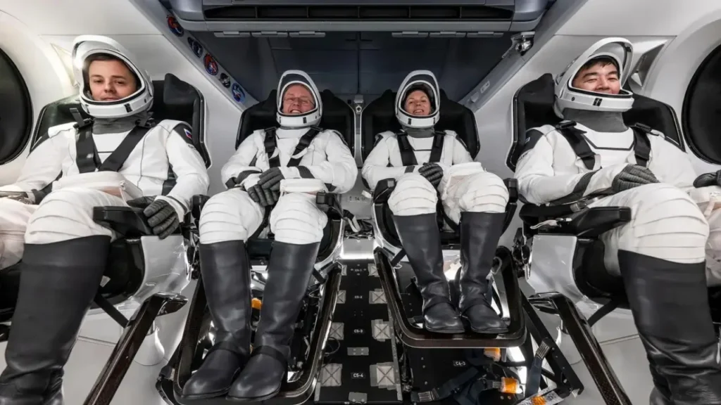 Four astronauts in SpaceX spacesuits are seated inside the Crew Dragon capsule as part of their Crew-11 mission to the International Space Station.