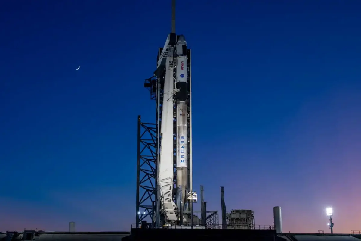 SpaceX Falcon 9 rocket on launch pad with crescent moon in the sky
