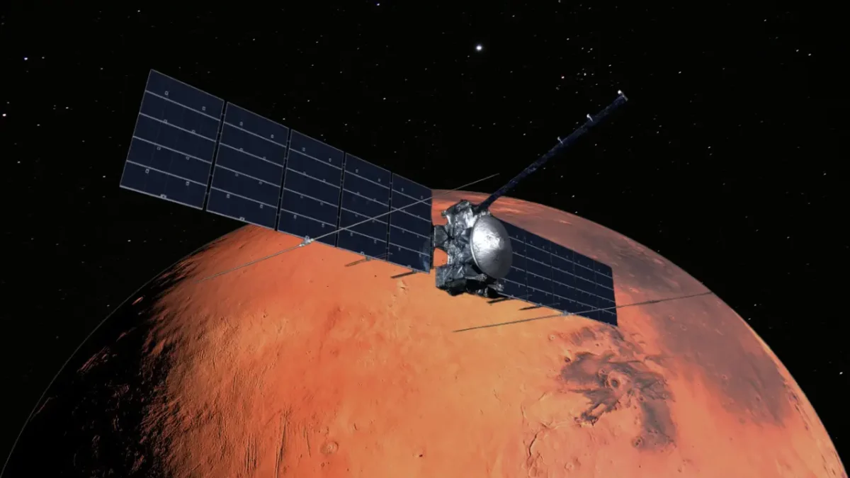 Artist’s rendering of NASA’s Europa Clipper spacecraft flying past the red planet Mars, with large solar panels extended and radar antennas visible.