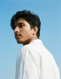 Aesthetic boy portrait in white shirt under bright daylight, minimal clean background, cinematic tone
