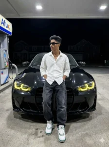 Stylish young man posing in front of black luxury car at night with neon headlights, cinematic car AI photo editing inspiration for boys