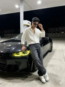 Stylish young man posing in front of black luxury car at night with neon headlights, cinematic car AI photo editing inspiration for boys